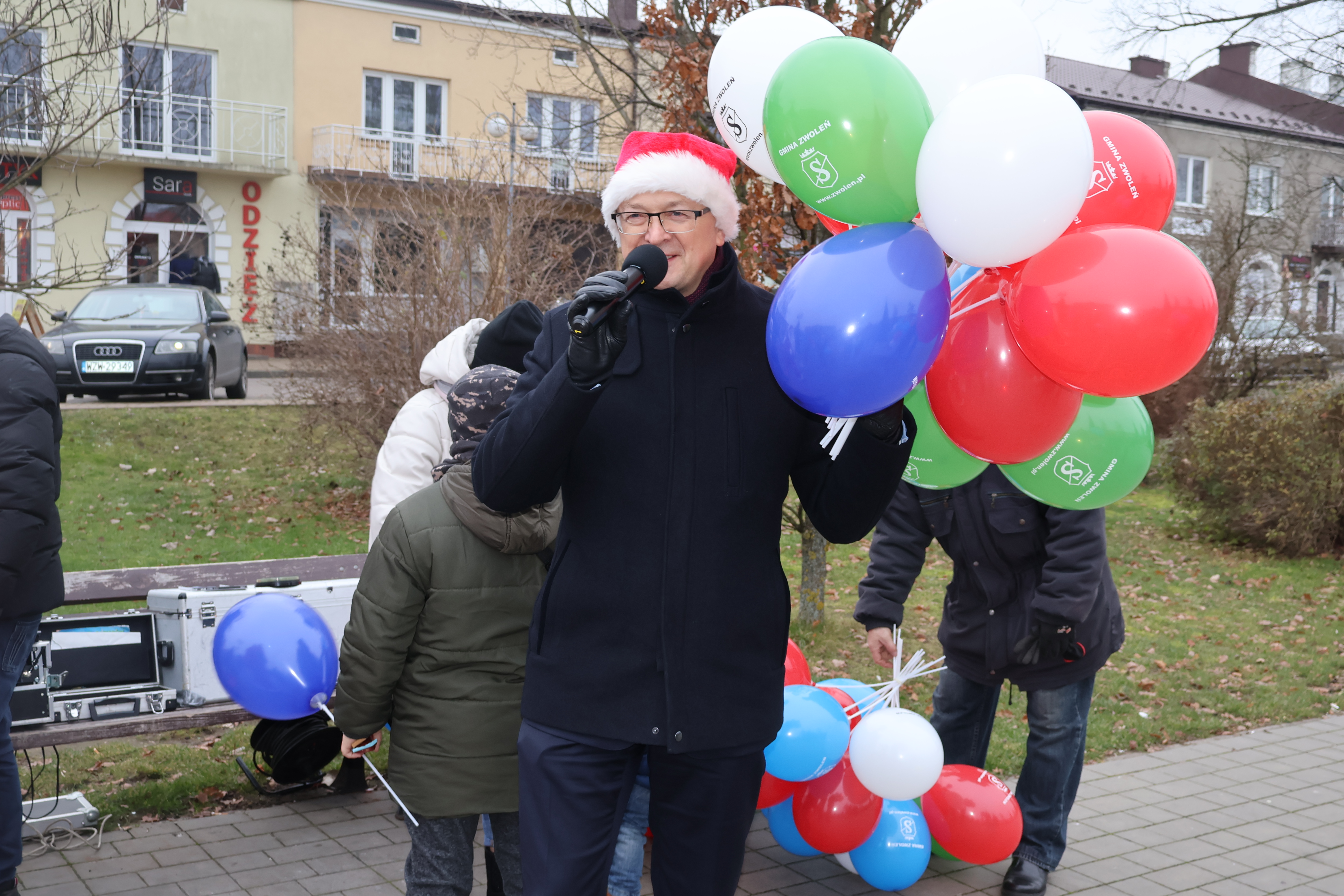 Burmistrz Zwolenia z balonami w ręku wita przybyłe na rynek dzieci. 