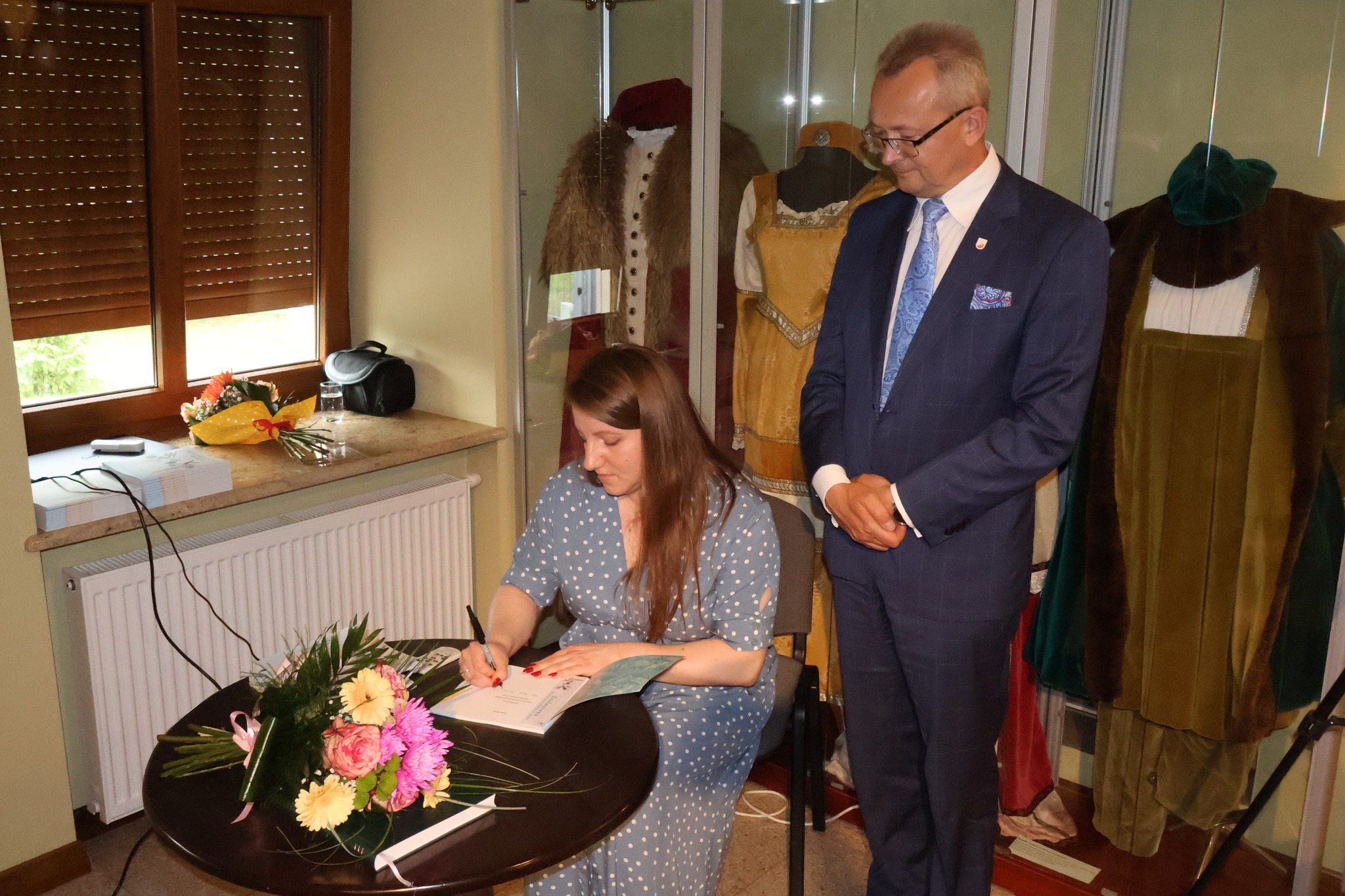 Pracownica muzeum Kinga Mazur podpisuje katalog burmistrzowi Zwolenia 