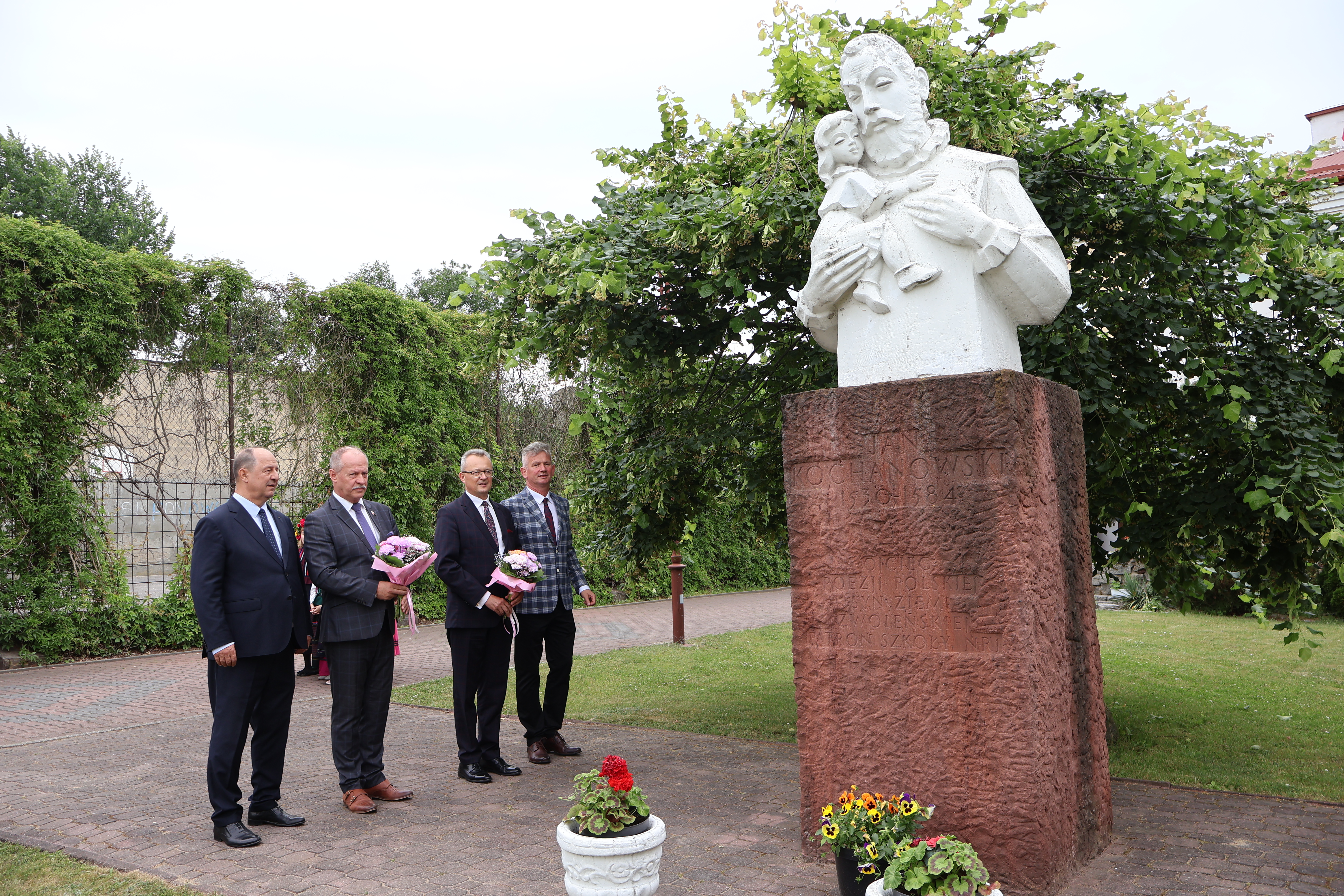 4 mężczyzn stoi przed pomnikiem Jana Kochanowskiego 